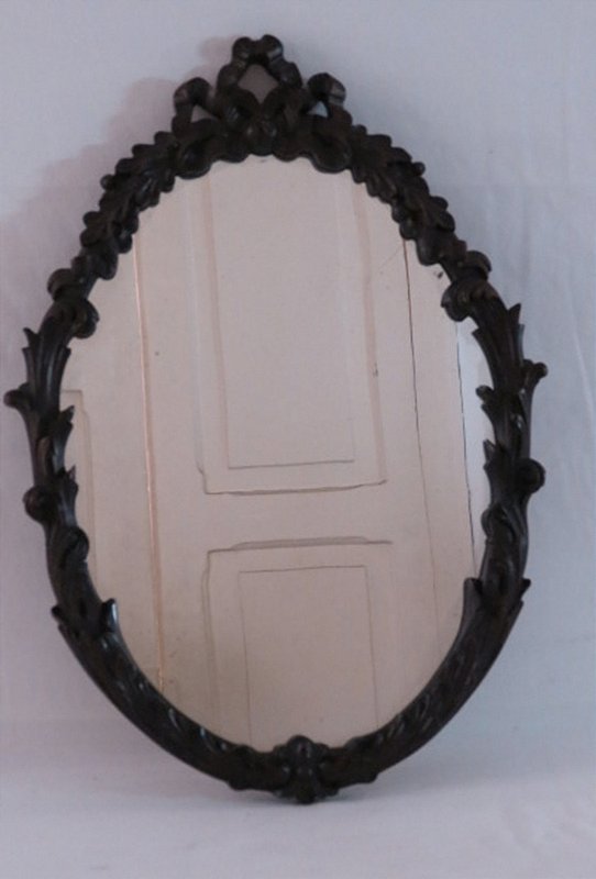 Belo e antigo espelho oval , moldura em madeira nobre ricamente entalhado em guirlandas, florais e laçarotes. Med.: 56 cm. x 40 cm.
