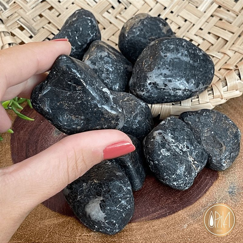 Turmalina Negra Rolada Opala Store sobre superfície em ambiente de meditação, pedra preta natural polida