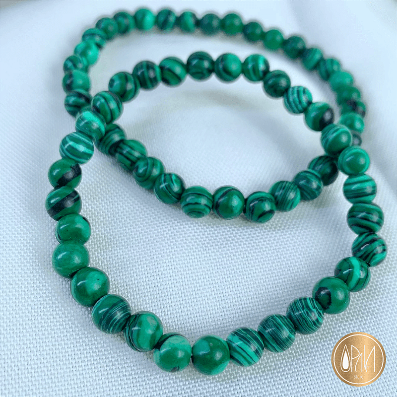 Pulseira Malaquita 6mm Opala Store em uso, esferas verdes em fio de silicone duplo, close no pulso